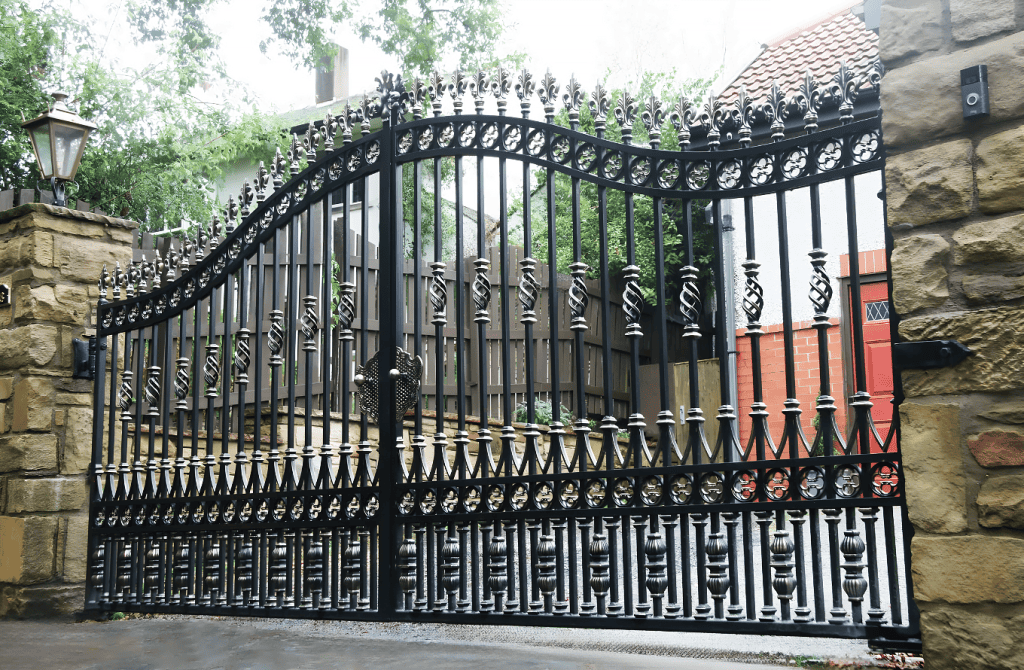 ornate wrought iron driveway gates with decorative scrollwork between stone pillars